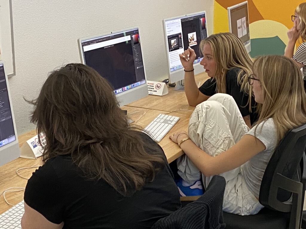 Three students looking at design software on a computer